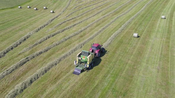 Aerial shot of tractor making haystacksSwiss countryside alt