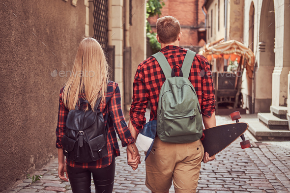 Handsome skater and his girlfriend walking around an old narrow streets of Europe. - Stock Photo - Images