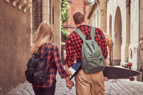 Handsome skater and his girlfriend walking around an old narrow streets of Europe. - Stock Photo - Images
