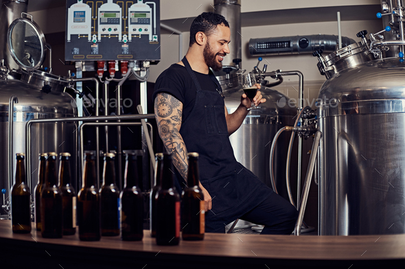 Portrait of a stylish bearded man standing behind the counter in the brewery