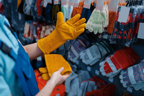 Young man in work gloves in warehouse with cargo trolley Stock
