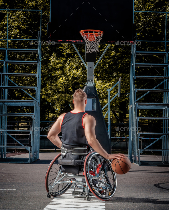 Cripple basketball player in a wheelchair plays on open gaming ground.