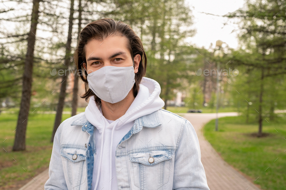 Young man in casualwear and protective mask walking down road in park