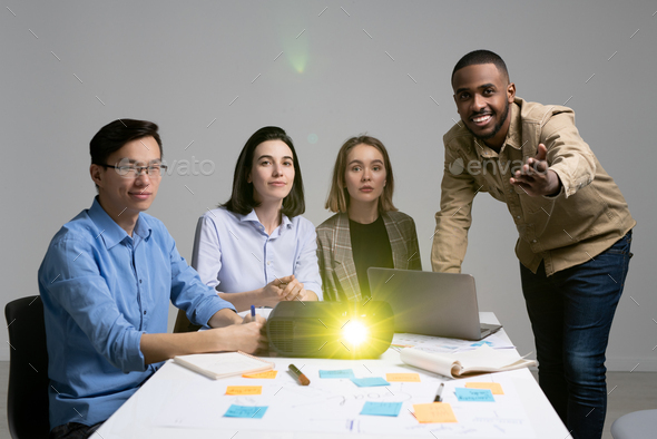 Young black man pointing at you while making presentation to group of colleagues