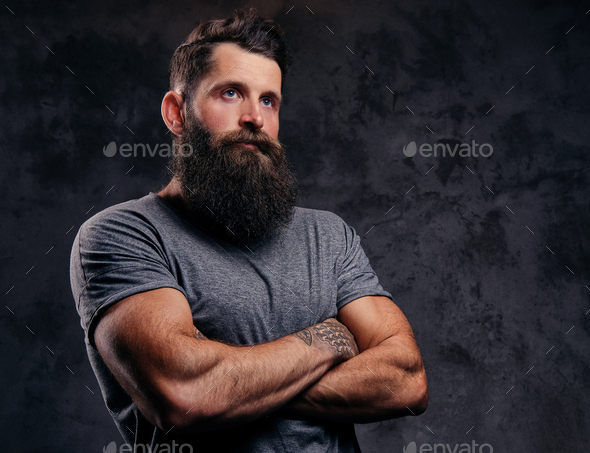 Portrait of a hipster with full beard and stylish haircut, dressed in a gray t-shirt in a studio