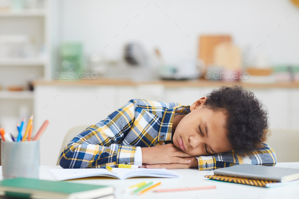 African-American Boy Sleeping on Desk while Studying