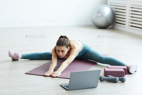 Young Woman Stretching Legs during Online Work Out