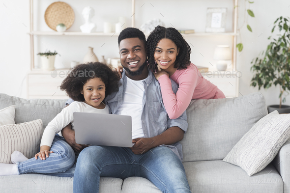 Smiling Black Parents And Little Daughter Posing With Laptop At Home
