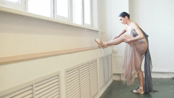 Ballerina in Stage Dress Stretching Leg in Vertical Split Near Window in Class