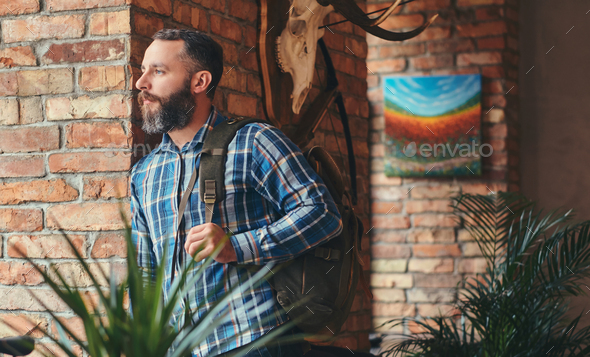 Handsome bearded hipster male in a blue fleece shirt and jeans with backpack