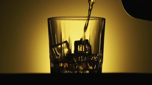 Alcohol Pouring in Glass From Bottle. Rum Flowing From Brown Bottle. alt