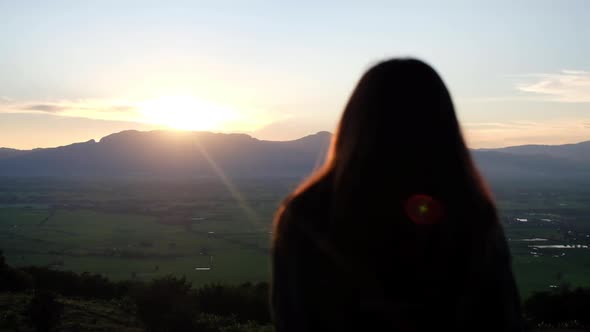 Slow motion rear view of a woman watching sunset and mountain views in the evening