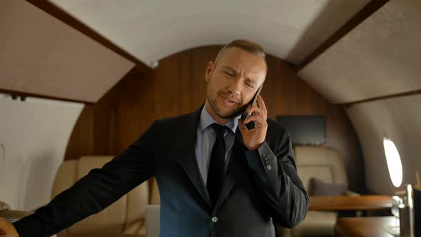 Private Jet Business Journey Concept. Businessman Talking on Mobile Phone. alt