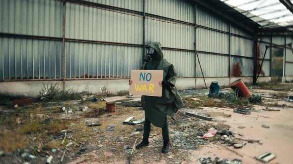 Military Man with Gas Mask and No War Placard in a Nuclear Site Destroyed By War alt