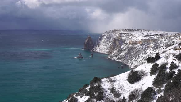 Snow Covered Rocky Cliffs Over Sea alt