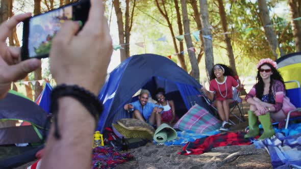 Man clicking pictures of his friends with mobile phone at music festival alt