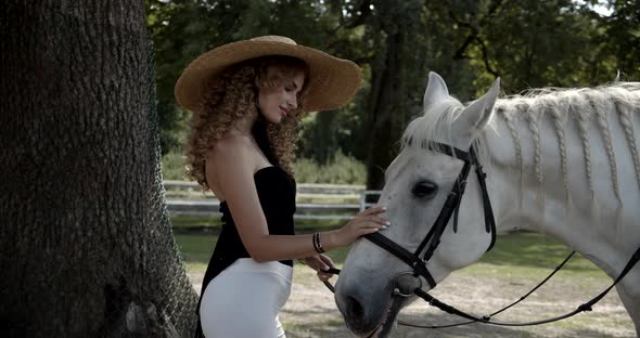 Beautiful Girl In A Hat Stroking A White Horse alt