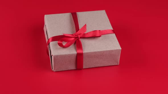 Rotating Gift Box with Red Ribbon and Bow on Red Background