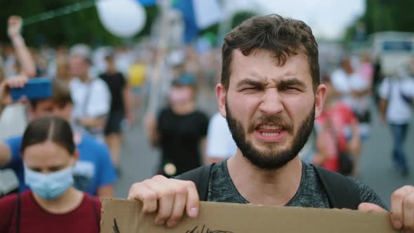 Demonstration beard man on anti government rally picket resist, rebel waves fist alt