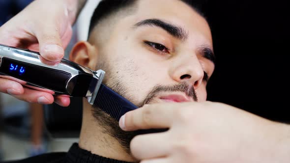 Closeup of a Customer Shaving with an Electric Razor in a Barbershop alt