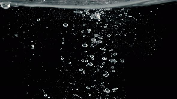 Soda water bubbles splashing underwater and floating water drop in black background. Motion picture