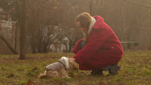 Lady with Long Hair Pets Small Fuzzy Dog in Grey Jacket alt