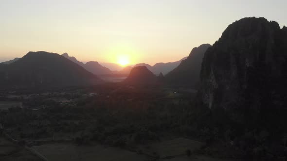 Aerial: Vang Vieng backpacker travel destination in Laos, Asia. Sunset over scen alt