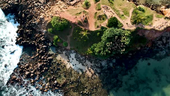 Aerial drone of Mirissa Beach at sunset golden hour. Parrot Rock with waves on sandy beach. Mirissa, alt