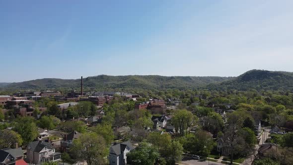 Drone view over established neighborhood in midwest city with bluffs and a bright blue sky.