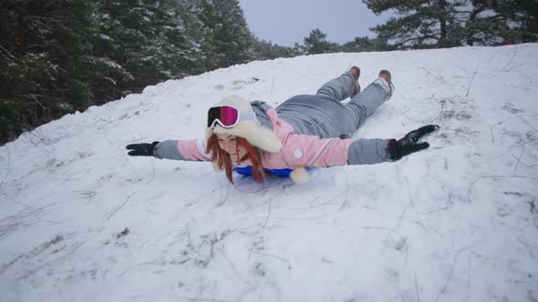Active Winter Vacation Happy Woman Slides Down Hill on Sled While Relaxing in a Snowy Forest