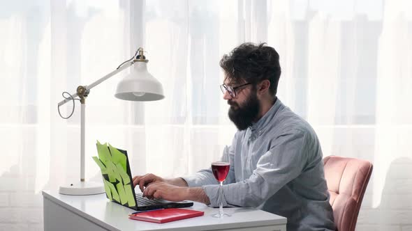 Man Types and Then Drink a Glass of Wine and Looks Happily at the Screen alt