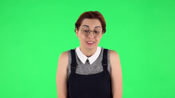 Portrait of Funny Girl in Round Glasses Is Smiling and Expressing She Innocent. Green Screen alt