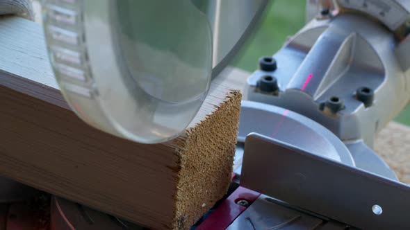 DIY Project Woodworker in Gloves Cuts Off 4X4 Wooden Post on Mitre Saw Close-up alt