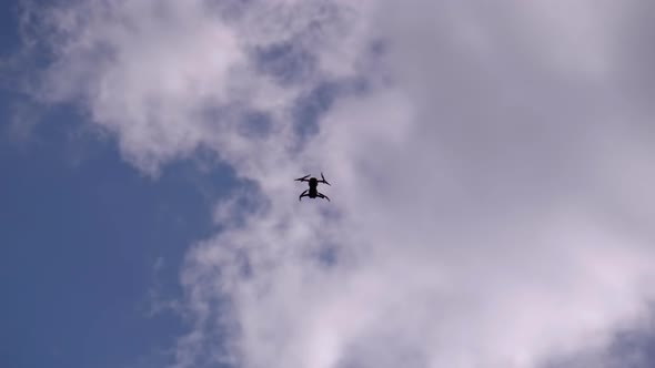 Silhouette of a Drone on a Background of Blue Sky with Clouds That Flies in the Air alt