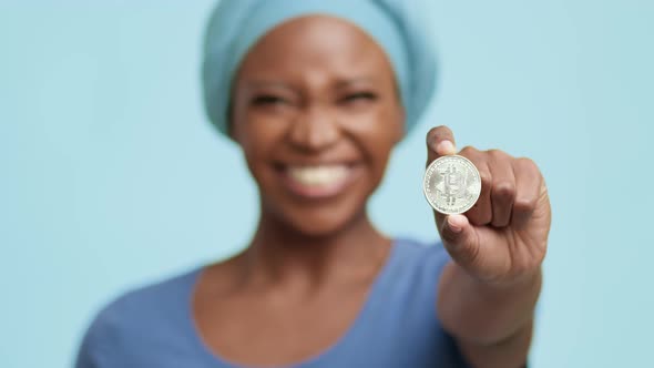 African American Lady Showing Silver Bitcoin Standing On Blue Background alt