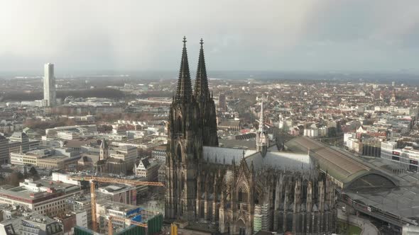 AERIAL: Circling Around Beautiful Cologne Cathedral with Central Train Station in Beautiful Hazy alt