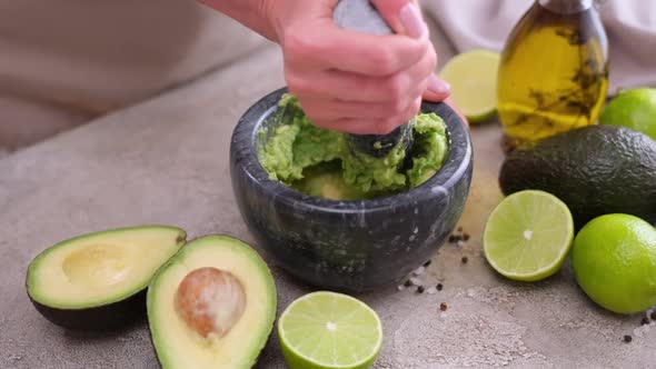 Making Guacamole Sauce  Woman Mashing Avocado in a Marble Mortar with Pestle at Domestic Kitchen alt