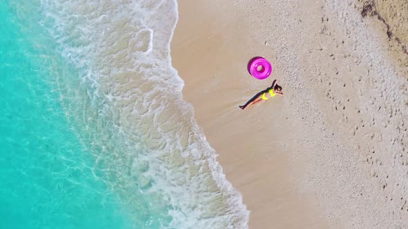 Aerial View of Young Woman with Pink Swim Ring on the Sandy Beach
