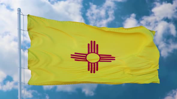 New Mexico Flag on a Flagpole Waving in the Wind Blue Sky Background alt