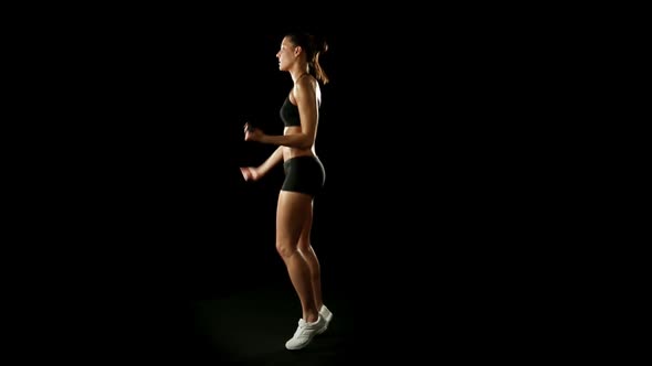 Young Athletic Woman Wearing Sporstwear is Exercising Jumping with Weights Slow Motion