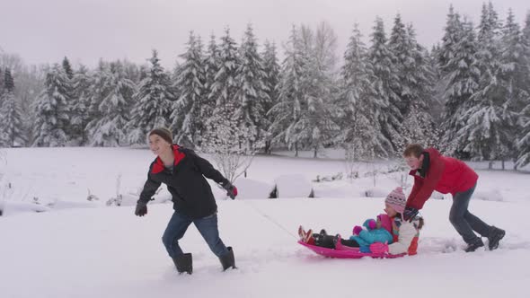 Kids playing and pushing sled in winter snow