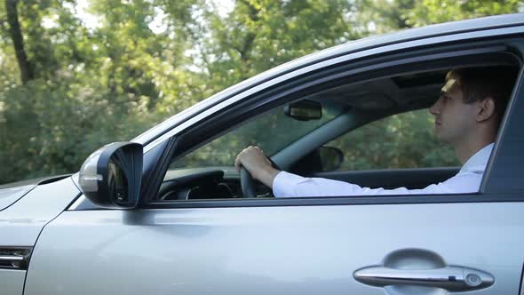 Handsome Young Man Driving Car on Rural Road alt
