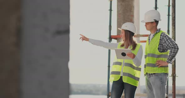 Engineers or Architects Have a Discussion at Construction Site Looking Through the Plan of alt