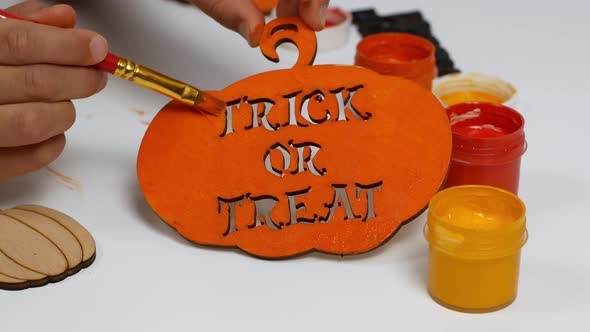 Children make their own Halloween decor. Children paint a pumpkin orange with the inscription alt