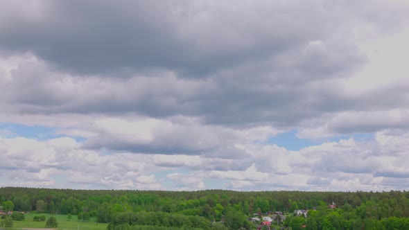Amazing view buildings on green fields between green forest trees and flowing river under blue sky. alt