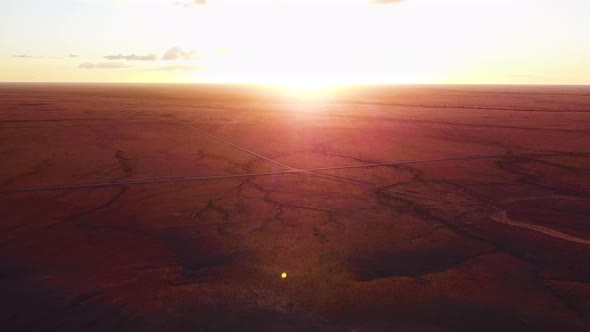 High panning aerial shot of incredible sunset over immense red earth plains of the Australian outbac alt