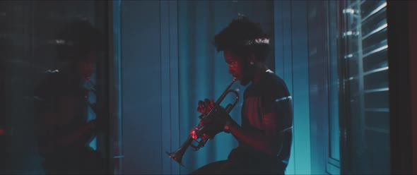A young trumpeter plays the trumpet in his apartment alt
