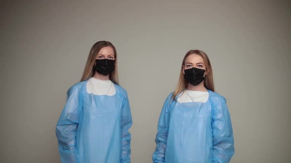 Two Young Girls Doctors Remove Special Protective Clothes and Rejoice Isolated on White Background