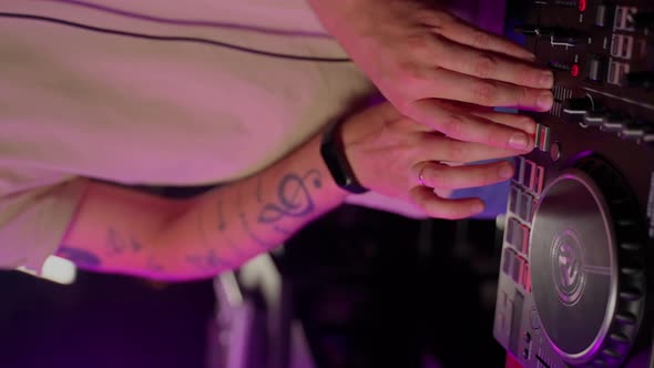 Close up DJ using controller console to mix music list in club. Caucasian deejay person alt
