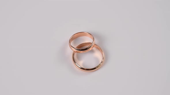 Two Wedding Rings Spin on a White Background alt